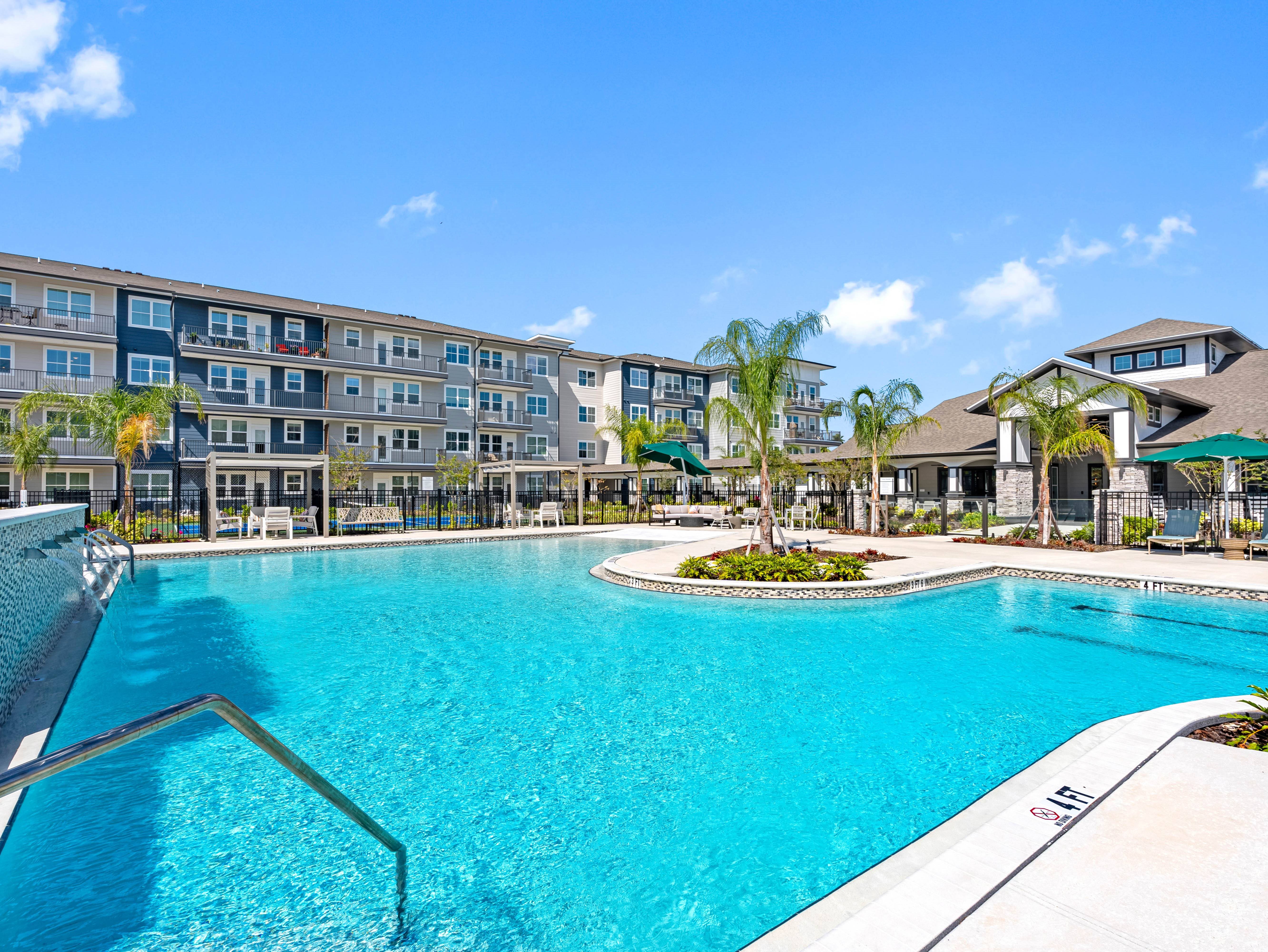 A large swimming pool in front of a building with a clear blue sky.